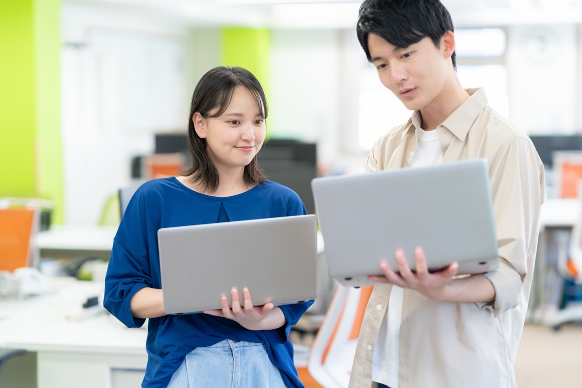 オフィスでノートパソコンを持って話す二人